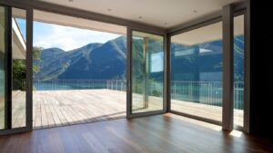 A spacious room with large, energy-efficient doors opens onto a wooden deck, offering views of a lake and mountain landscape under a clear sky—an inviting feature often found in modern Arizona homes.