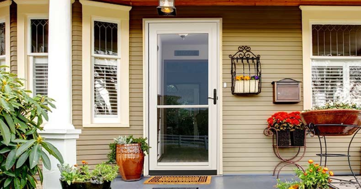 A Phoenix home with a front porch featuring a glass storm door, potted plants, a doormat, a wall-mounted mailbox, and decorative flower arrangements near the entrance.