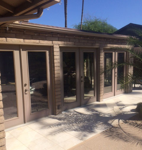 A patio with sliding glass doors and a palm tree in need of replacement doors.